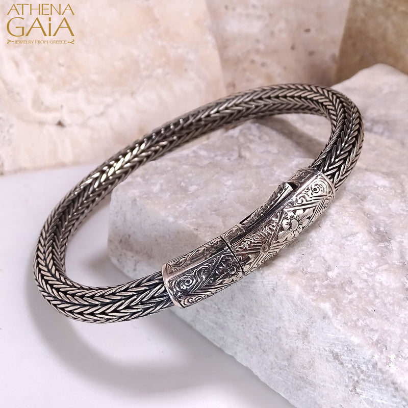 Woven silver bracelet with detailed floral clasp design, handcrafted in Greek artisan style.