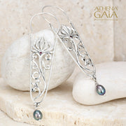 Silver filigree earrings with floral design, red gemstone accents, and blue pearl drops.
